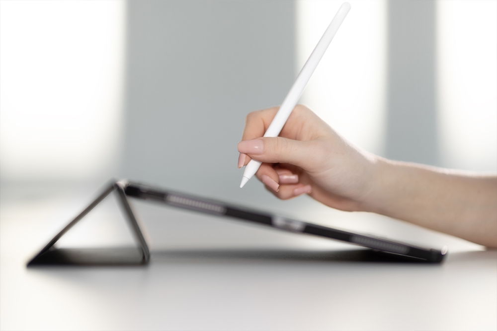 Eine Hand schreibt mit einem digitalen Stift auf einem Tablet.
